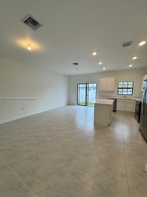 kitchen with open floor plan, white cabinets, a center island, and visible vents