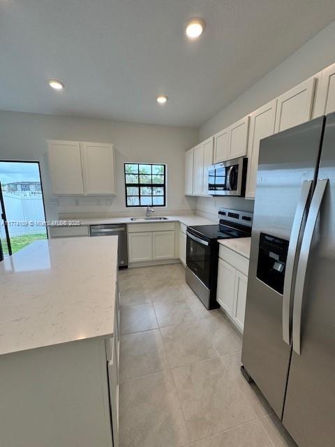 kitchen featuring light stone countertops, recessed lighting, appliances with stainless steel finishes, a sink, and light tile patterned floors