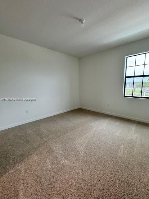 carpeted spare room featuring baseboards