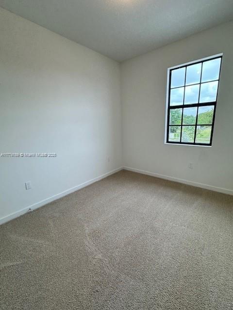carpeted empty room featuring baseboards