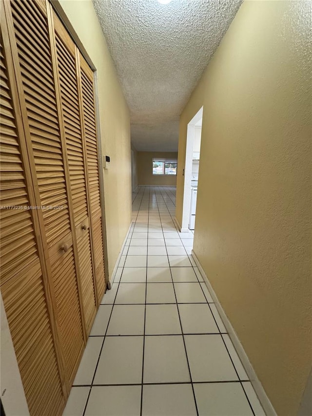 505 NW 177th St Unit 103, Miami Gardens, FL 33169 - hall featuring baseboards, a textured ceiling, a textured wall, and light tile patterned floors