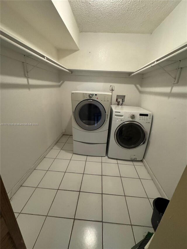 505 NW 177th St Unit 103, Miami Gardens, FL 33169 - laundry room featuring washer and clothes dryer, a textured ceiling, laundry area, light tile patterned floors, and baseboards
