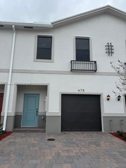 townhome / multi-family property featuring decorative driveway, stucco siding, and an attached garage
