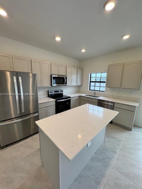 kitchen featuring light tile patterned floors, stainless steel appliances, a center island, gray cabinetry, and a sink