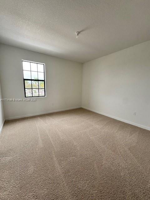 spare room featuring carpet, baseboards, and a textured ceiling