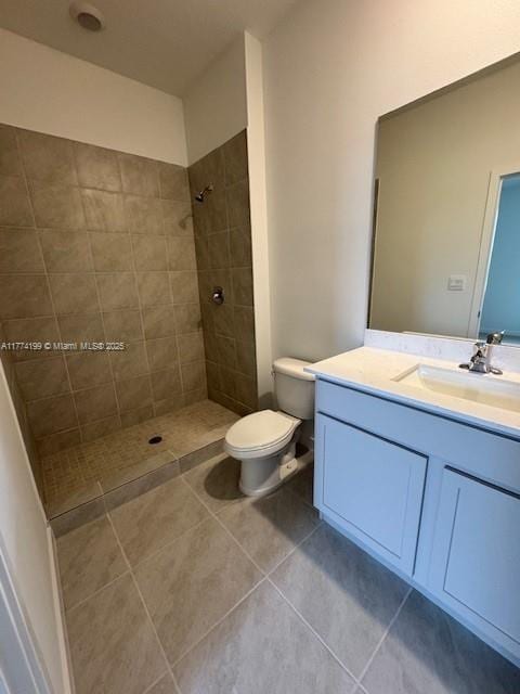 full bathroom with toilet, vanity, tile patterned floors, and a tile shower