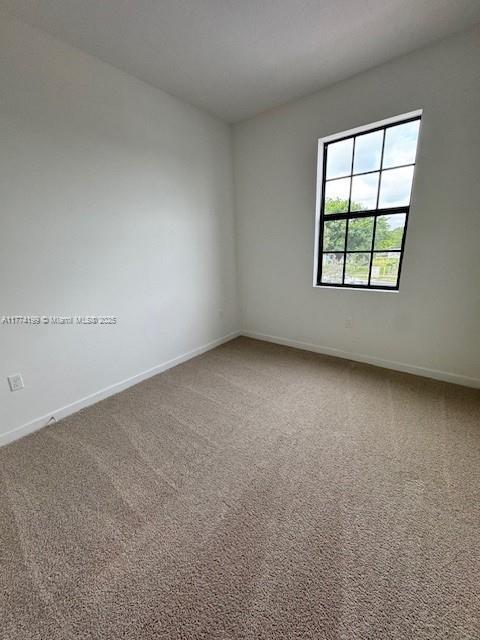 spare room featuring baseboards and carpet flooring
