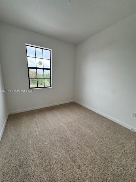 unfurnished room featuring light colored carpet and baseboards
