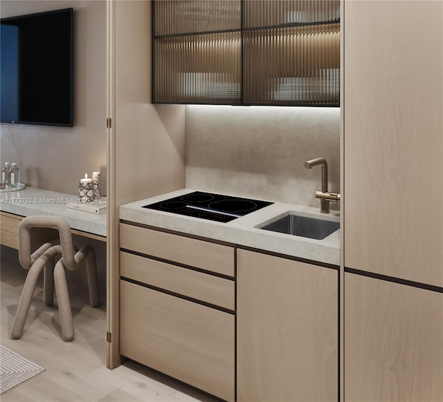 kitchen featuring light countertops, a sink, black electric stovetop, and light wood-type flooring