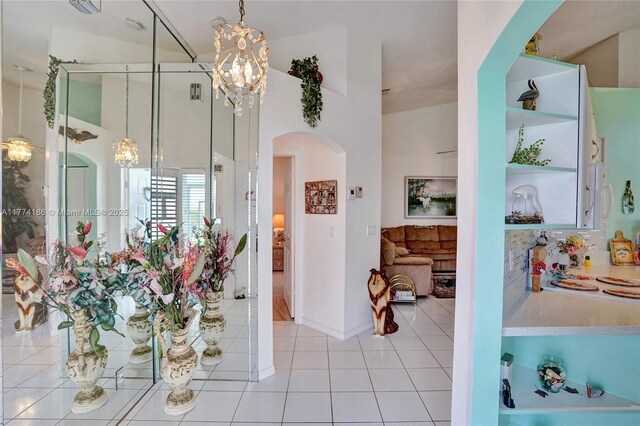 interior space featuring a notable chandelier, tile patterned flooring, baseboards, and a towering ceiling