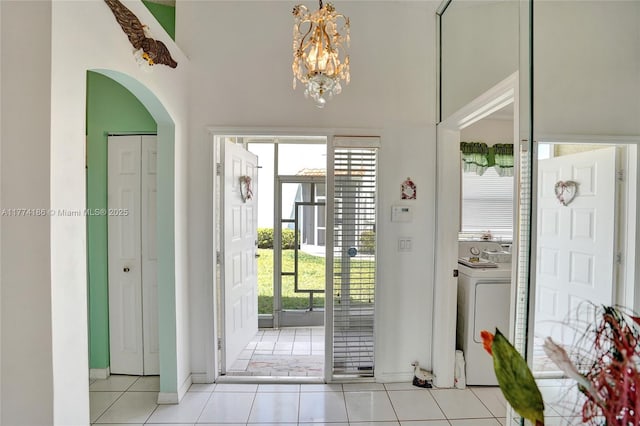 foyer with arched walkways, a notable chandelier, washer / dryer, and baseboards