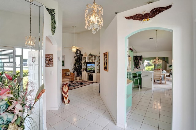 hallway featuring light tile patterned floors, baseboards, arched walkways, and an inviting chandelier
