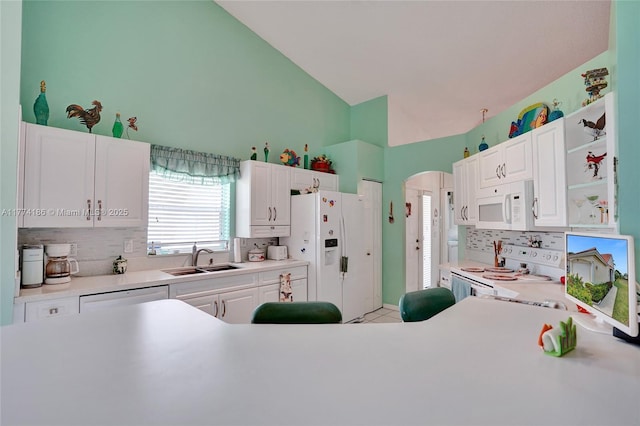 kitchen featuring white appliances, tasteful backsplash, white cabinetry, light countertops, and a sink
