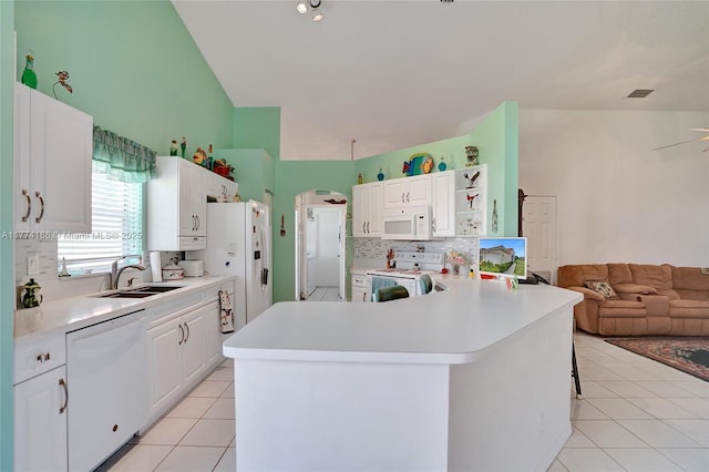 kitchen featuring open floor plan, white appliances, light tile patterned floors, decorative backsplash, and a sink