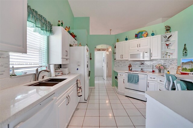 kitchen with tasteful backsplash, a sink, light countertops, white appliances, and white cabinetry