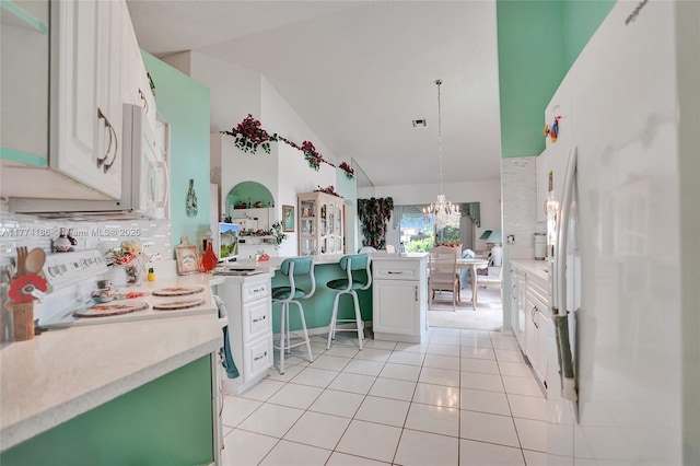 kitchen with freestanding refrigerator, vaulted ceiling, light tile patterned flooring, light countertops, and a notable chandelier
