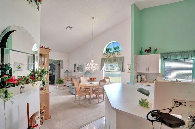 kitchen with an inviting chandelier, light countertops, visible vents, high vaulted ceiling, and light colored carpet
