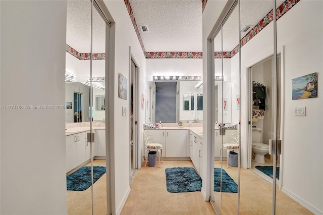 bathroom with vanity, a textured ceiling, and toilet