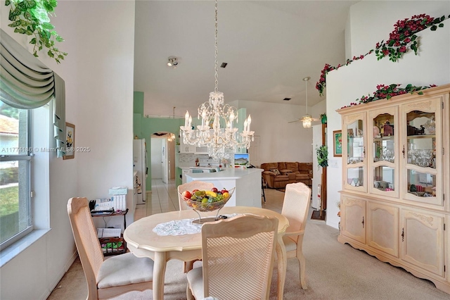 dining space with light colored carpet, high vaulted ceiling, arched walkways, and a notable chandelier