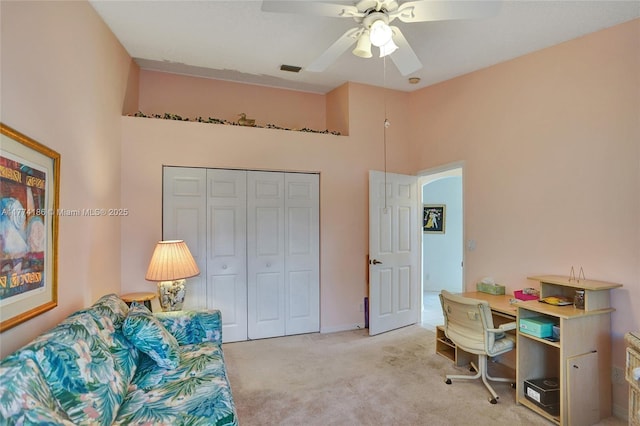 home office with carpet flooring, a towering ceiling, visible vents, and a ceiling fan