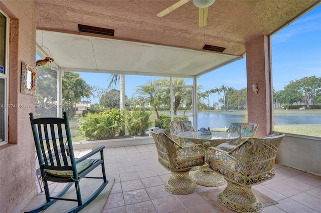 sunroom / solarium featuring a water view, plenty of natural light, and ceiling fan