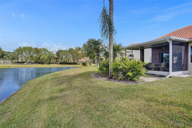 view of yard featuring a sunroom and a water view