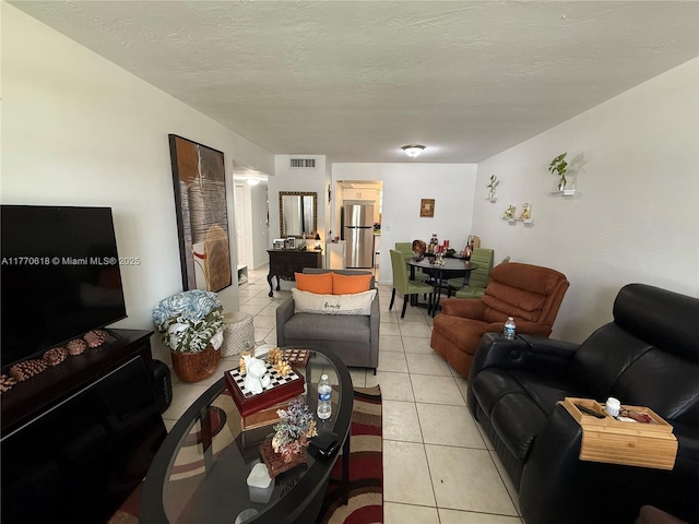 living room with light tile patterned flooring, a textured ceiling, and visible vents