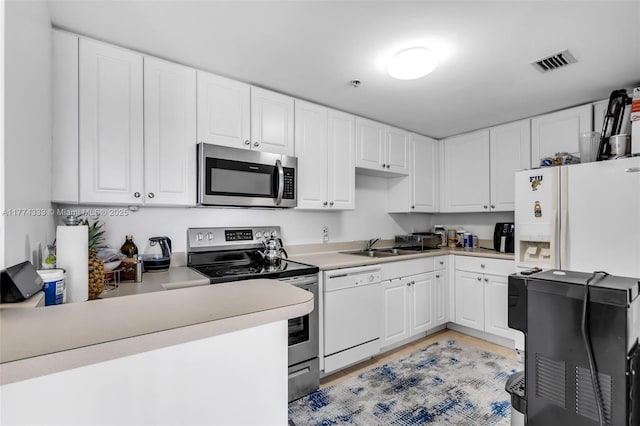 kitchen featuring appliances with stainless steel finishes, white cabinets, and light countertops