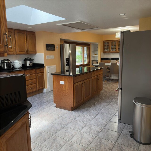 1950 S Tanner Rd, Orlando, FL 32820 - kitchen with freestanding refrigerator, stainless steel refrigerator with ice dispenser, a center island, dark countertops, and brown cabinetry