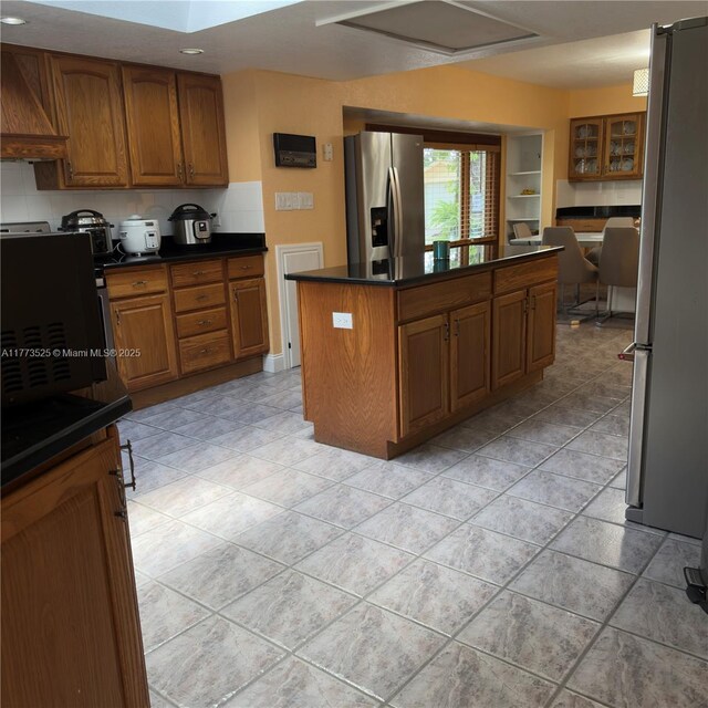 1950 S Tanner Rd, Orlando, FL 32820 - kitchen with stainless steel fridge with ice dispenser, freestanding refrigerator, brown cabinetry, a kitchen island, and dark countertops