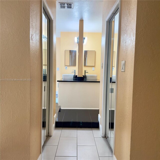 1950 S Tanner Rd, Orlando, FL 32820 - hall featuring a textured wall, light tile patterned floors, a sink, and baseboards