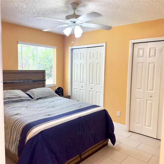 1950 S Tanner Rd, Orlando, FL 32820 - bedroom featuring a textured ceiling, two closets, light tile patterned floors, and a ceiling fan