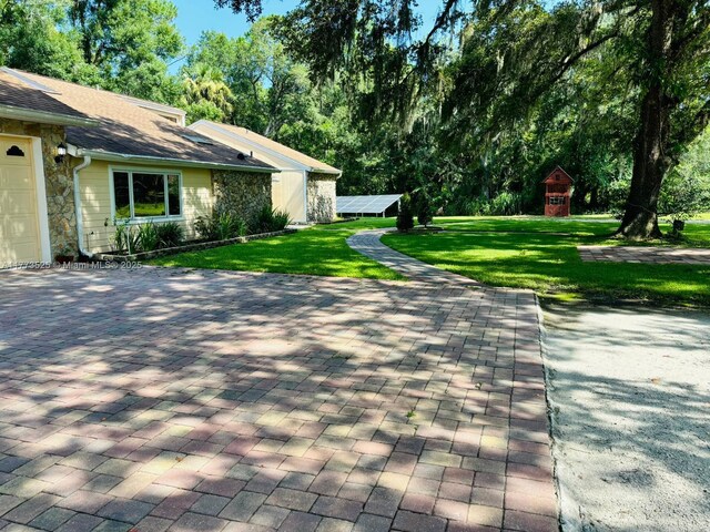 1950 S Tanner Rd, Orlando, FL 32820 - view of side of property featuring stone siding, a lawn, and a shingled roof