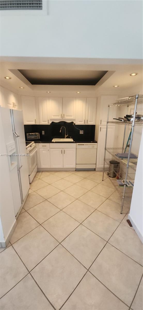 1950 S Ocean Dr Unit 6G, Hallandale Beach, FL 33009 - kitchen with a tray ceiling, a sink, white appliances, white cabinetry, and recessed lighting