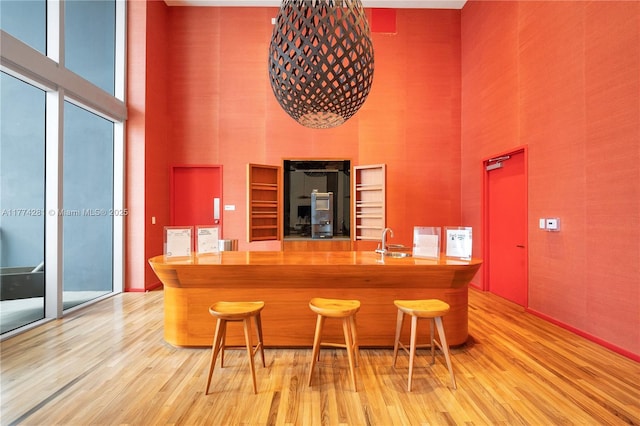 1300 Brickell Bay Dr Unit 601, Miami, FL 33131 - bar featuring light wood-style floors, a sink, and a towering ceiling