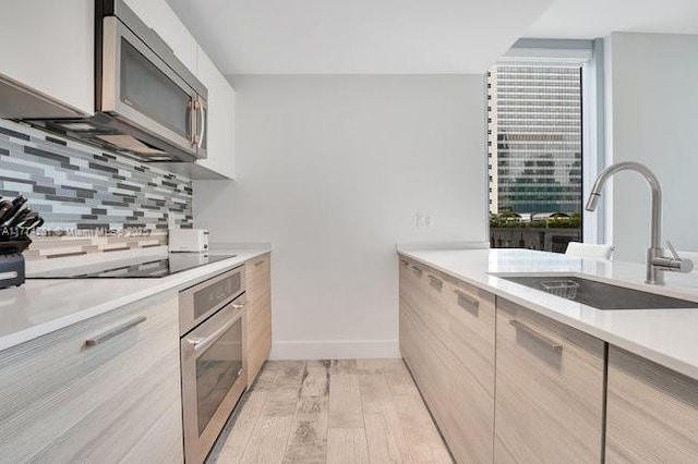 1300 Brickell Bay Dr Unit 601, Miami, FL 33131 - kitchen with a sink, light wood finished floors, stainless steel appliances, decorative backsplash, and modern cabinets