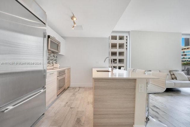 1300 Brickell Bay Dr Unit 601, Miami, FL 33131 - kitchen with light wood-style floors, open floor plan, light countertops, a sink, and stainless steel appliances