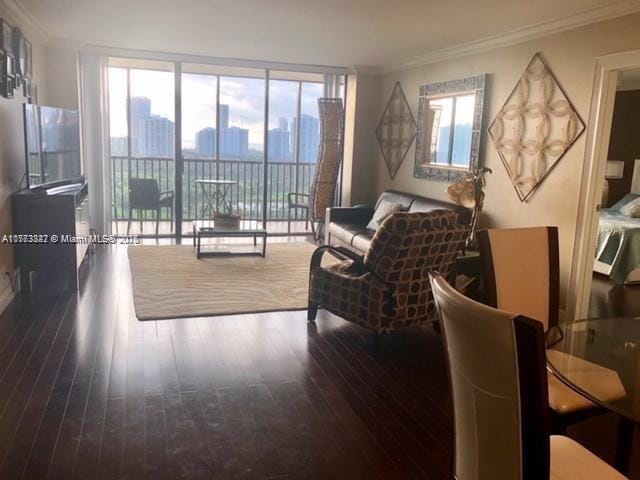 living room featuring wood finished floors, a view of city, ornamental molding, and a healthy amount of sunlight