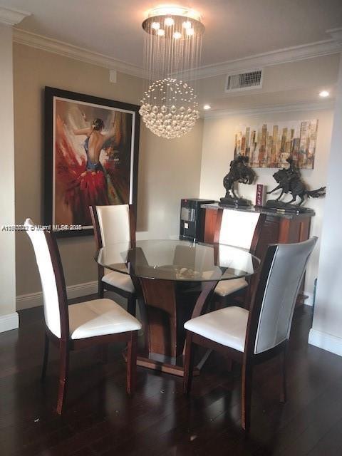 dining space with visible vents, crown molding, wood finished floors, and a notable chandelier