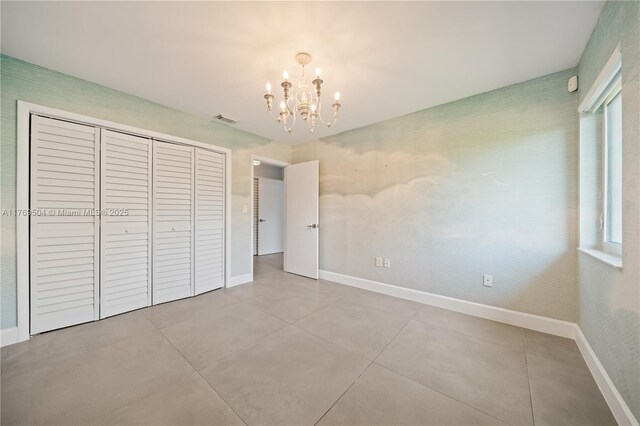6881 SW 94th Ave, Miami, FL 33173 - unfurnished bedroom with a chandelier, baseboards, a closet, and tile patterned flooring