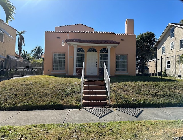 mediterranean / spanish-style house with a front yard, a porch, stucco siding, and fence
