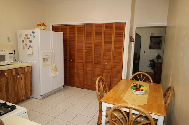 kitchen with light tile patterned floors, light countertops, and white appliances