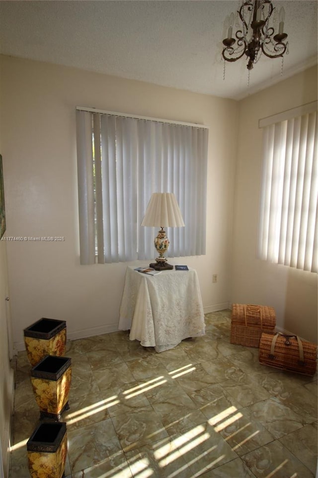empty room featuring baseboards and a chandelier