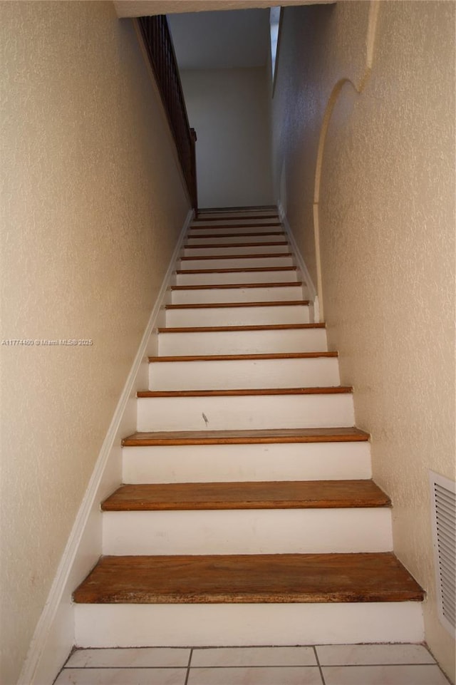 stairs featuring visible vents and a textured wall