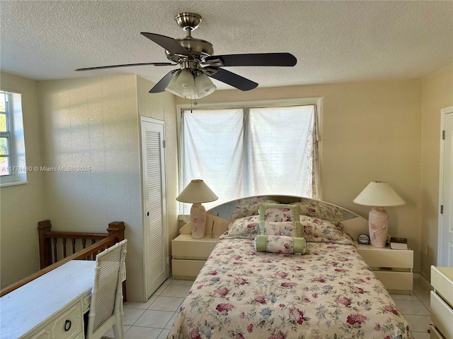bedroom with a closet, light tile patterned floors, a textured ceiling, and ceiling fan