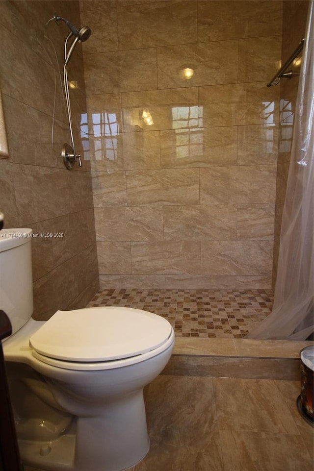 bathroom featuring toilet, tile walls, and a stall shower