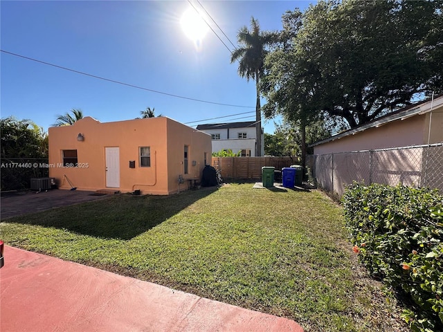 view of yard with central AC, a fenced backyard, and a patio