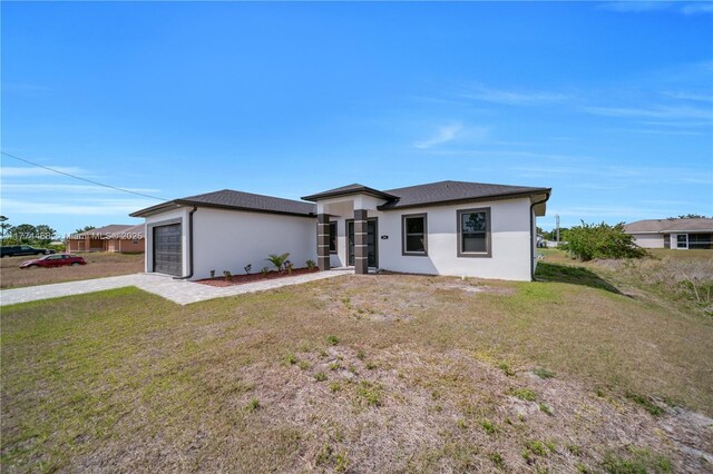 3114 39th St SW, Lehigh Acres, FL 33976 - view of front of house featuring stucco siding, an attached garage, a front yard, and driveway