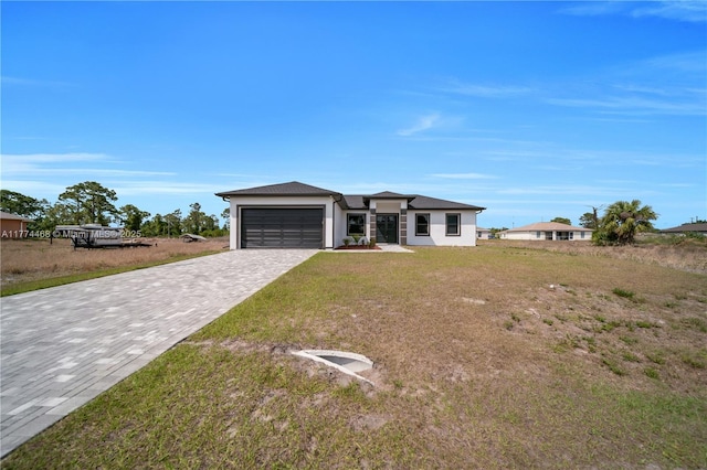 3114 39th St SW, Lehigh Acres, FL 33976 - prairie-style house featuring stucco siding, a garage, a front lawn, and decorative driveway