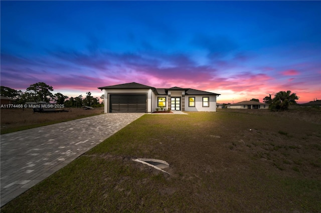 3114 39th St SW, Lehigh Acres, FL 33976 - view of front of house with a lawn, a garage, stucco siding, and decorative driveway